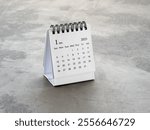 A January 2025 desk calendar for the organizer to plan and reminder, standing on cement floor background, loft style. White small table calendar with the page of the first month, Happy new year 2025.