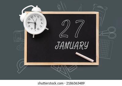 january 27. 27th day of month, calendar date. Blackboard with piece of chalk and white alarm clock on green background. Concept of day of year, time planner, winter month.