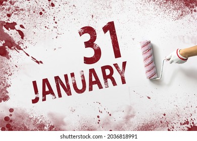 January 31st . Day 31 of month, Calendar date. The hand holds a roller with red paint and writes a calendar date on a white background. Winter month, day of the year concept