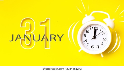 January 31st . Day 31 of month, Calendar date. White alarm clock with calendar day on yellow background. Minimalistic concept of time, deadline. Winter month, day of the year concept