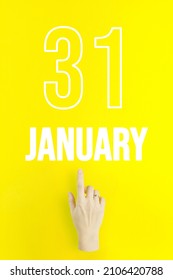 January 31st . Day 31 of month, Calendar date.Hand finger pointing at a calendar date on yellow background.Winter month, day of the year concept
