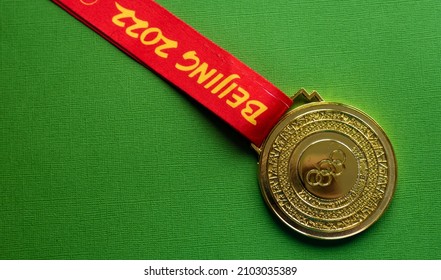 January 6, 2021, Beijing China. Gold Medal Of The XXIV Olympic Winter Games On A Green Background.