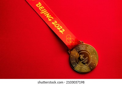 January 6, 2021, Beijing China. Gold medal of the XXIV Olympic Winter Games on a red background.