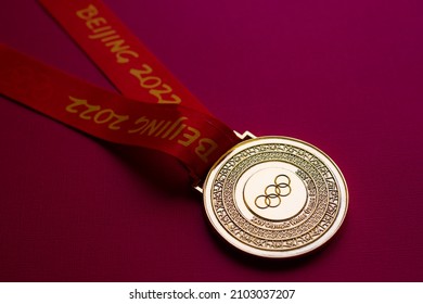 January 6, 2021, Beijing China. Gold medal of the XXIV Olympic Winter Games on a red background.