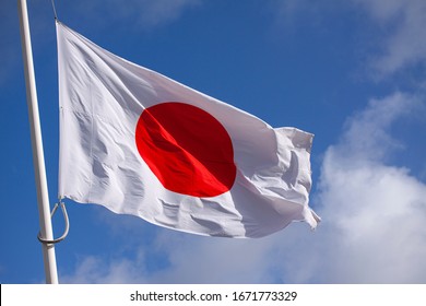 Japan flag waving in the wind against blue sky. Close up image. 