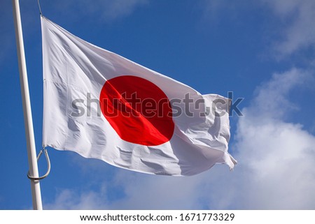 Japan flag waving in the wind against blue sky. Close up image. 