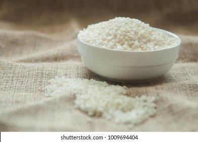 Japan rice grain in white bowl on hemp sack.
