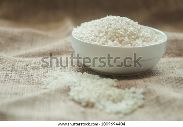 Japan rice grain\
in white bowl on hemp\
sack.