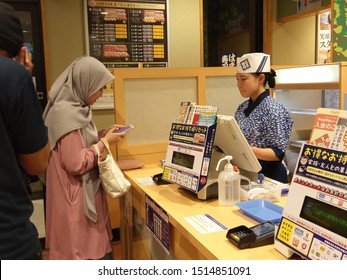 Japan - September 26, 2019 : Friendly Japanese Restaurant Cashier Waiting Payment From Customer. Content Asian Sushi Restaurant Employee Working With Client. Owner Concept