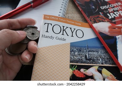 Japan Tourist Guide Book On Hand And Japan Coin. Jakarta, 2021.