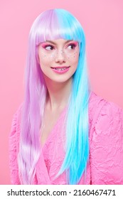 Japanese anime style. Beautiful girl with bright makeup and in colored violet-blue wig posing in stylish pink dress. Studio portrait on a pink background. Fashion. Hairstyle, hair coloring, make-up.