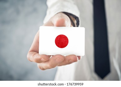 Japanese Businessman Holding Business Card With Japan Flag. International Cooperation, Investments, Business Opportunities Concept.