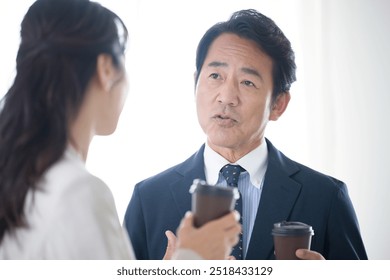 Japanese businessmen having a coffee break and standing around talking in their office. Image of managers and executives. - Powered by Shutterstock