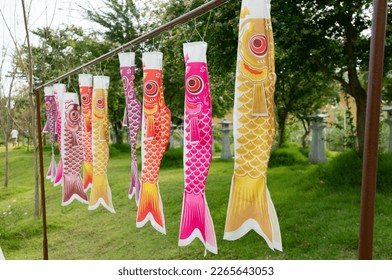 Japanese carp fish wind socks blow in the wind.Hanging on a wooden railing. Available in orange, pink and yellow. - Shutterstock ID 2265643053