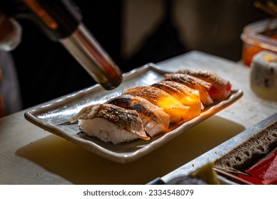 Japanese chef making aburi sear fired sushi set at sushi bar restaurant, close up selective focus

 - Powered by Shutterstock