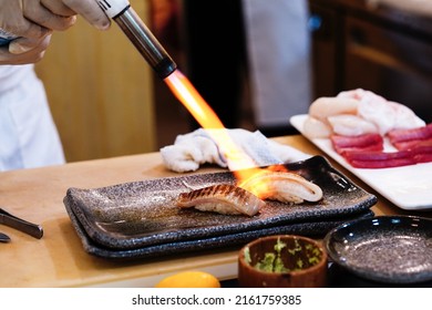 Japanese chef using kitchen torch burn on omakase sushi.