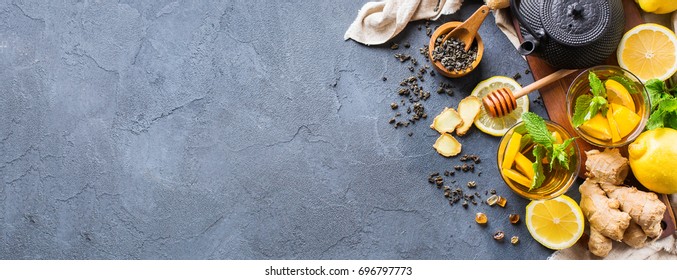 Japanese chinese tea teapot lemon ginger honey on a black table. Warm drink beverage infusion in glass for cold flu winter days, copy space background, top view flat lay
