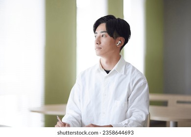 Japanese college student male studying using smartphone in university library - Powered by Shutterstock