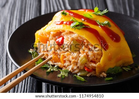 Japanese cuisine: omurice with rice, chicken and vegetables close-up on the table. horizontal
