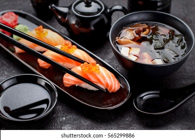 Japanese Cuisine. Salmon Sushi Nigiri And Miso Soup On Black Plate A Dark Table.