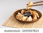 Japanese dumplings Gyoza with soy sauce. Chopsticks holding fried gyoza.