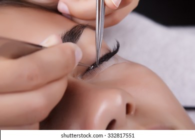 Japanese eyelash extensions. Long eyelashes. Beautiful dark-haired girl lies on a couch in the office of the master eyelash.
