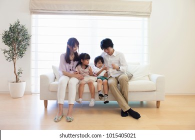 Japanese family sitting on the sofa - Shutterstock ID 1015405021