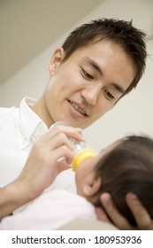 A Japanese father helping his child drink milk