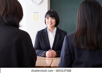 A Japanese Female Teacher Conducting A Three-way Interview In Her Classroom