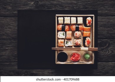 Japanese food restaurant, sushi maki gunkan roll plate or platter set. ?opy space, chopsticks, ginger, soy sauce, wasabi. Sushi at rustic wood background in take away, delivery box. Top view.  - Powered by Shutterstock