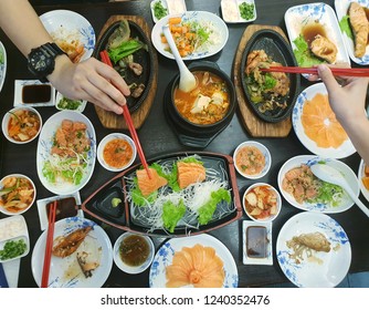 Japanese Food Style, Top View Of Hand Use Chopsticks Holding Salmon Slice With Shrimp Steak, Buta Steak, Sushi, Shrimp Salad, Teriyaki Sauce And Rice On The Table, Japan Food Set In Restaurant