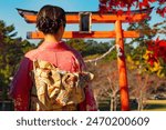 Japanese geisha with her back to camera. Woman in traditional Asian kimono. Geisha near gate to buddhist temple. Girl in national Japanese clothes. Geisha walks through summer Tokyo. Japanese culture