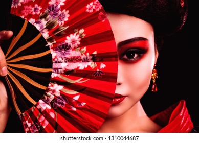 Japanese Girl In A Kimono With A Red Fan In Her Hands. The Image Of A Geisha