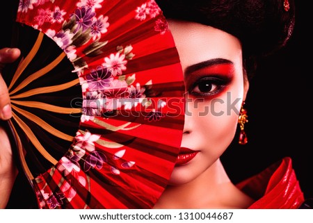 Japanese girl in a kimono with a red fan in her hands. The image of a geisha