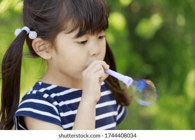 Japanese girl playing with bubble in the green (5 years old)