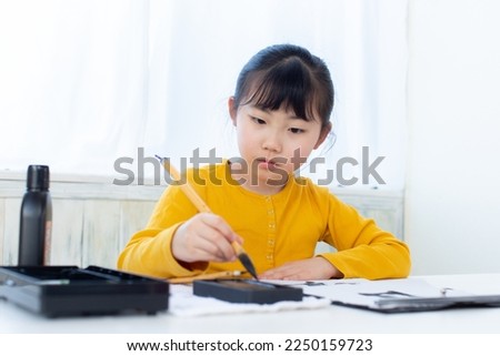 A Japanese girl practicing Japanese calligraphy