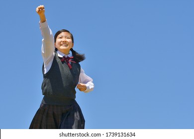 Japanese girl strikes a victory pose in the blue sky