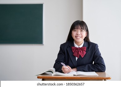 A Japanese junior high school girl studies in the classroom with a smile