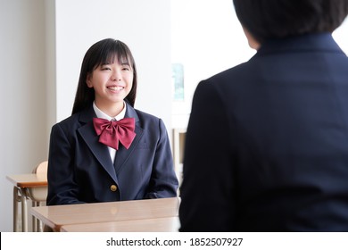 A Japanese junior high school girl meets with her teacher in the classroom