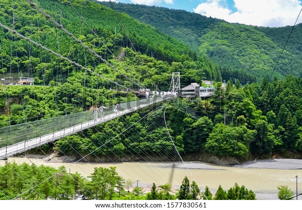 Japanese landscape with a suspension bridge\
between mountains