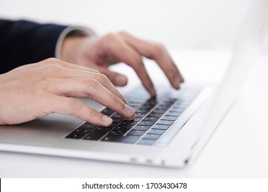 A Japanese Male Businessman Typing On A Laptop Computer.