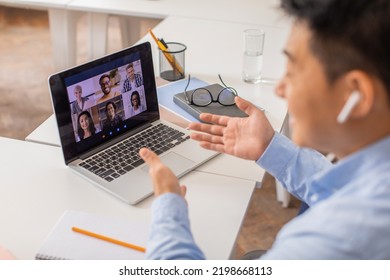 Japanese Male Teacher Video Calling Via Laptop Teaching Online A Group Of International Students Having Virtual Lecture At Workplace Indoor. E-Learning Concept. Selective Focus On Computer Screen