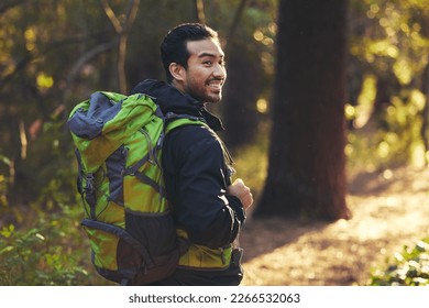 Japanese man, backpacker and hiking in forest nature, trekking woods or trees for adventure, relax workout or fitness exercise. Smile, happy and hiker walking in environment for healthcare wellness