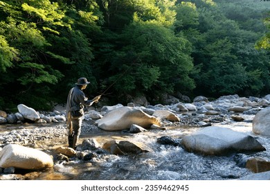 Japanese man fly fishing in a mountain stream in Japan - Powered by Shutterstock