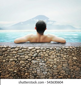 Japanese Man Soaking In Outdoor Onsen Hot Spring With Mt. Fuji View In Summer.