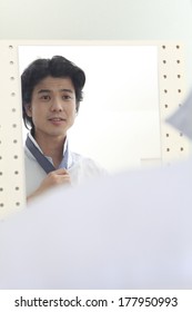 Japanese Man Tying A Tie While Looking In The Mirror