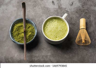 Japanese matcha green tea powder, a healthy natural product, antioxidant. Bamboo spoon and whisk. Gray background, close-up, top view.
