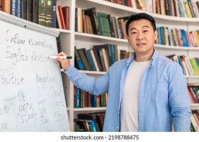 Japanese Middle Aged Male Teacher Standing Near Whiteboard Writing Lecture Looking At Camera Indoor. Online Class And Remote Online Education. E-Learning Concept