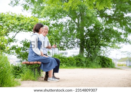 A Japanese middle-aged couple talking on a park bench,