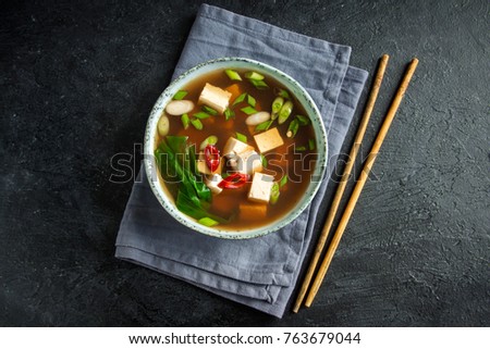 Japanese miso soup in ceramic bowl on black stone table, copy space. Asian miso soup with tofu.